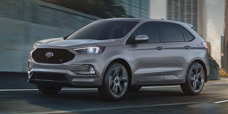 An image of the new Ford Edge in metallic gray, driving on a city street.