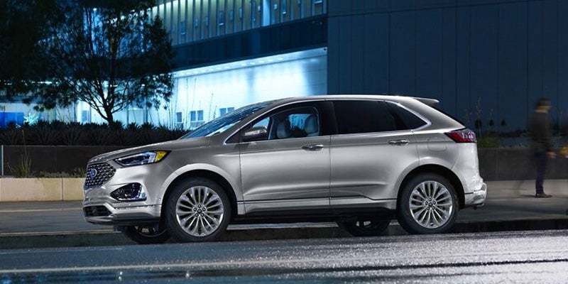 An image of a silver Ford Edge on a city street at night.